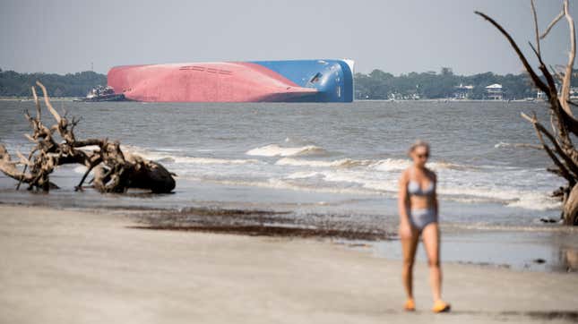 A woman walks along the beach at Jekyll Island as emergency responders work to rescue crew members from a capsized cargo ship on September 9, 2019 in St Simons Island, Georgia. A 656-foot vehicle carrier, the M/V Golden Ray departed the Brunswick port on Sunday and suffered a fire on board, capsizing in St. Simons Sound. 