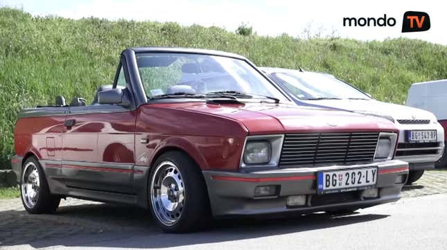 A lowered red Yugo convertible actually looking kinda badass on polished rims